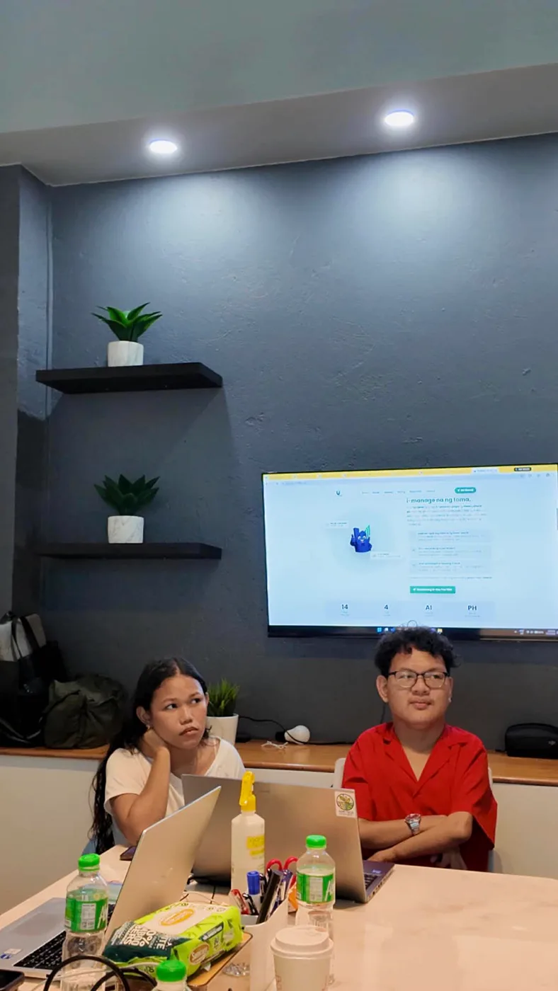 Daniel and a teammate at the UPAMATE office with the website on the wall screen